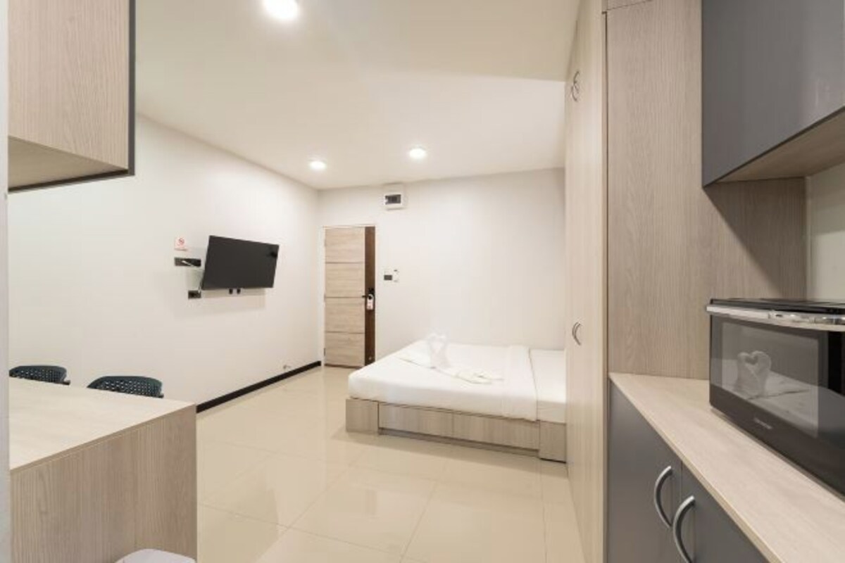 Una habitación de hotel moderna con cama, escritorio, televisor y microondas.