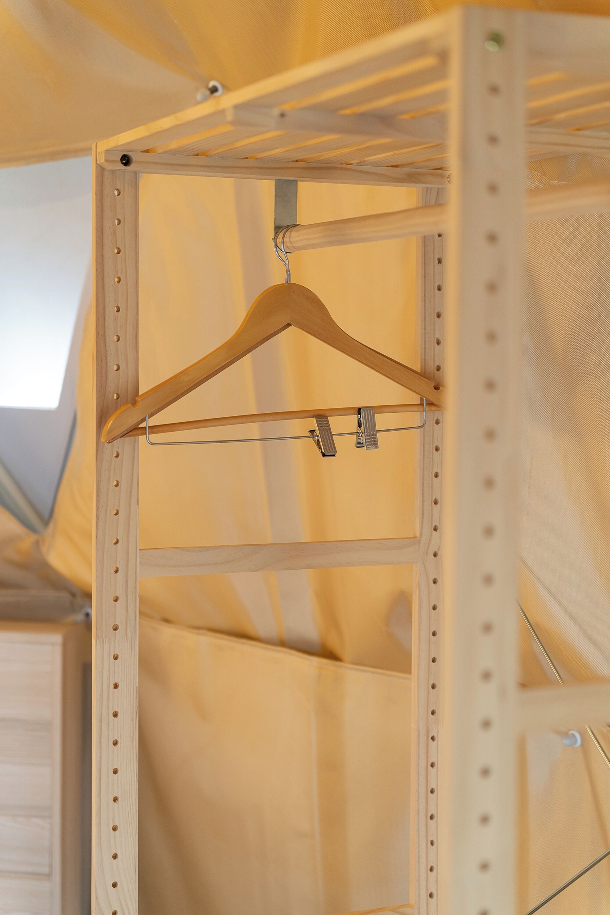 A wooden hanger rack with a metal clip, part of a room's interior structure.