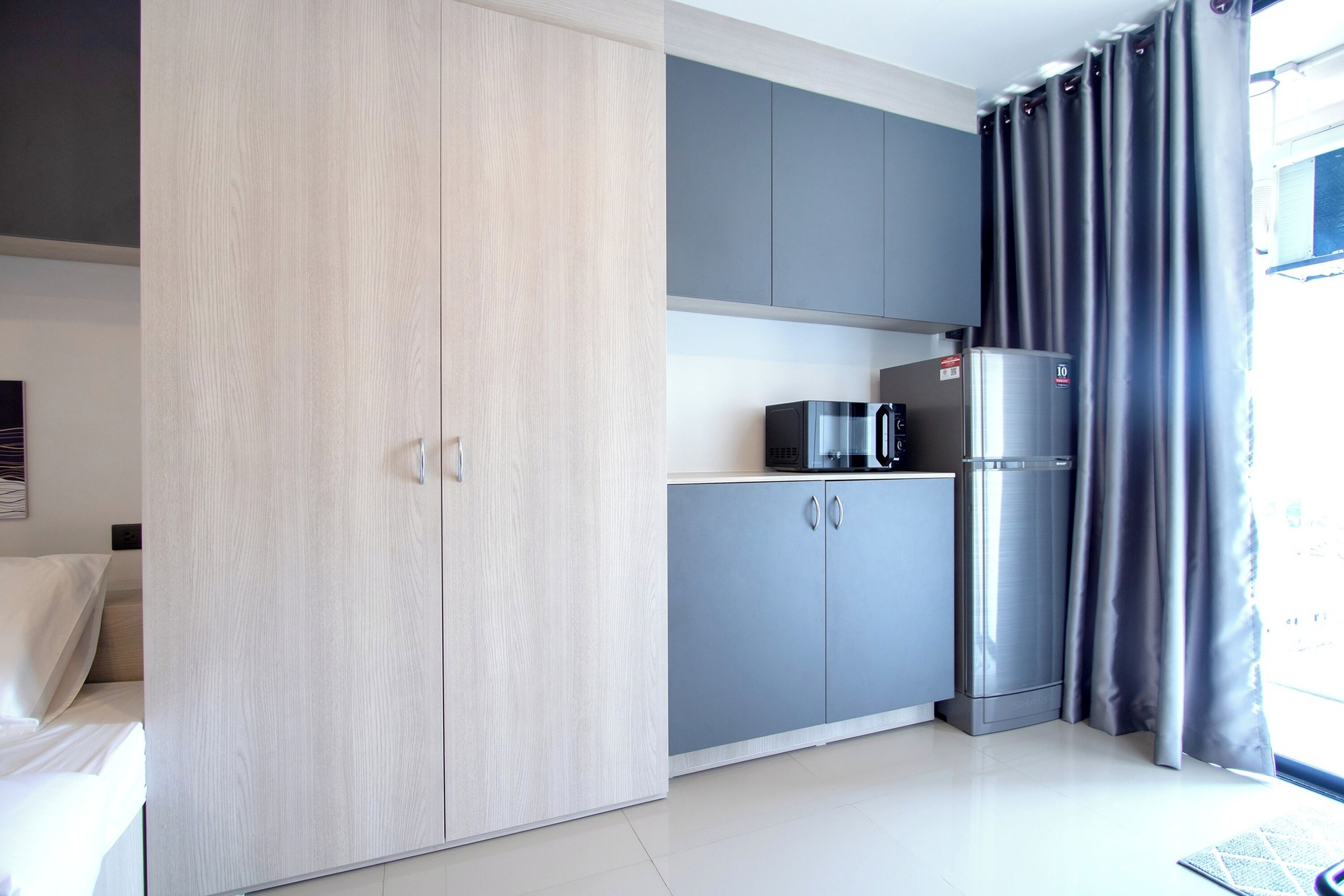 A modern kitchen with grey cabinets, a stainless steel refrigerator, and a microwave.
