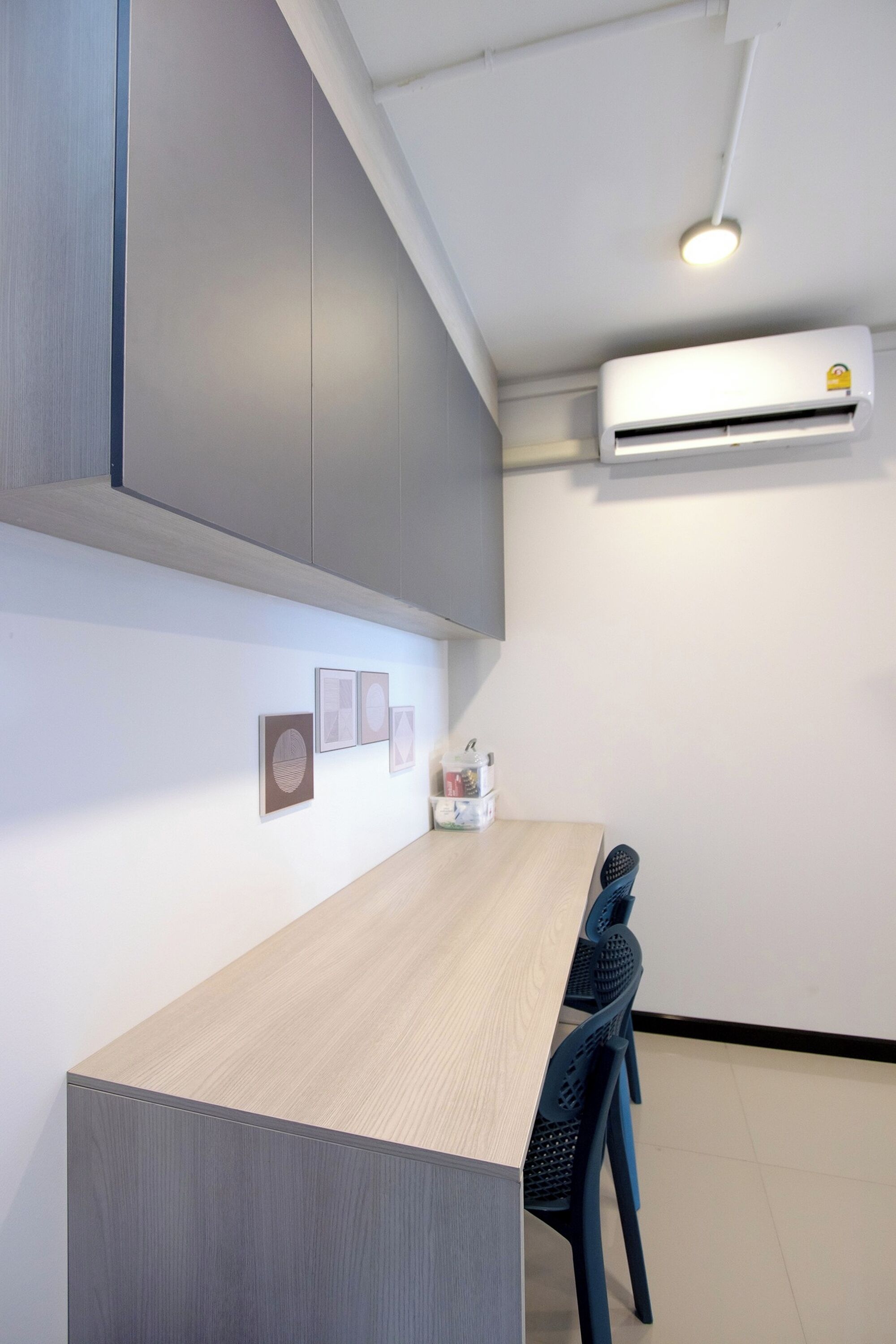 A modern kitchen with a wooden countertop, grey cabinets, and a built-in air conditioning unit.