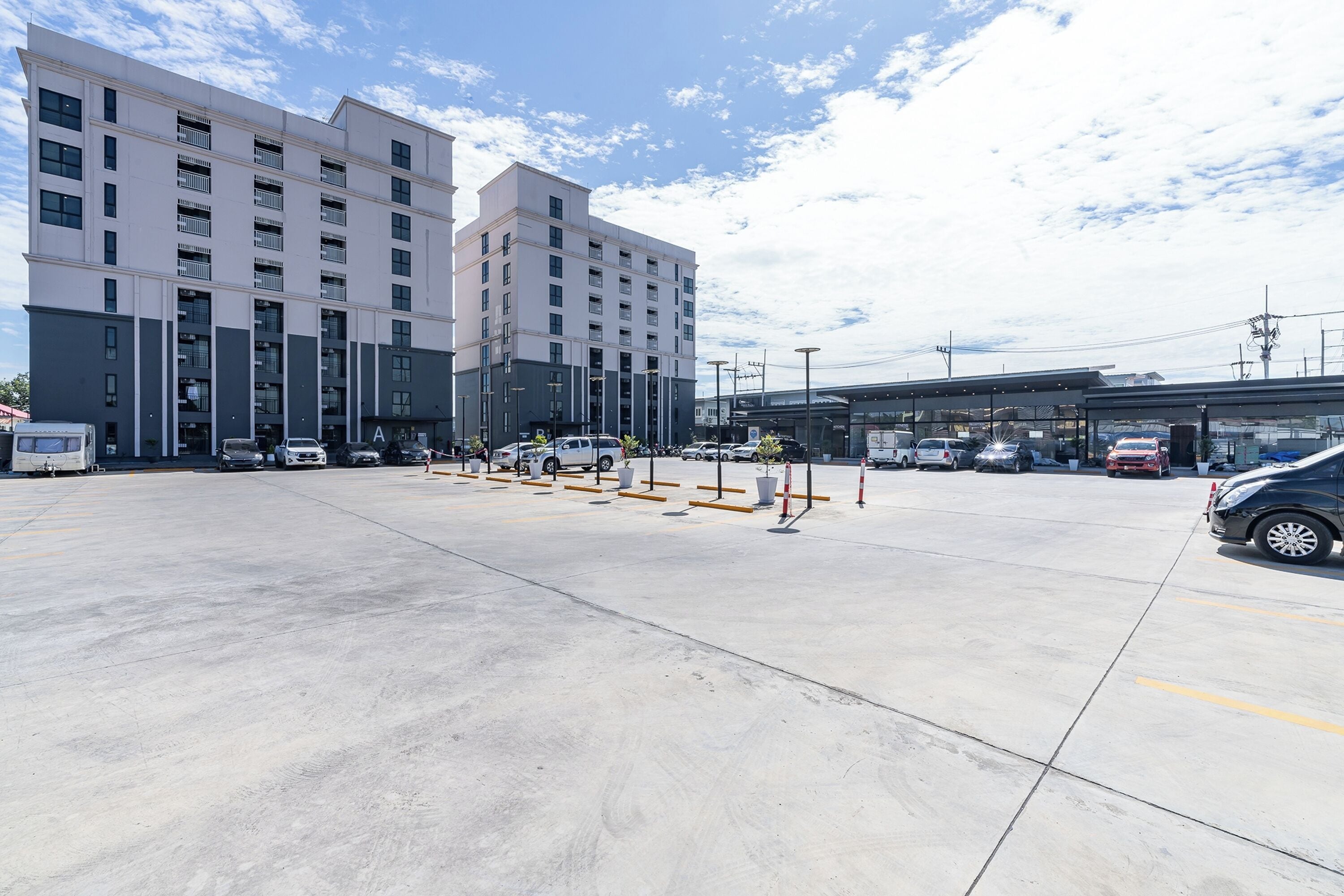 A parking lot with multiple cars and a building with several floors and balconies.
