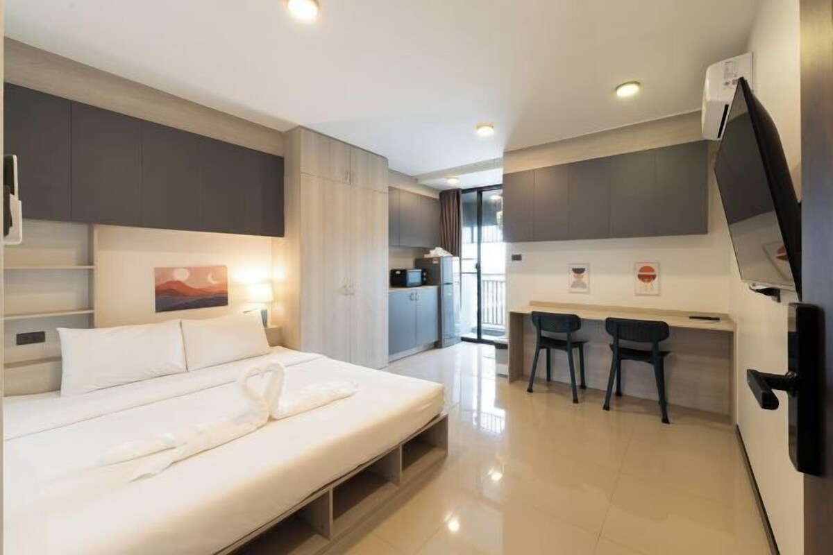 Une chambre d’hôtel moderne équipée d’un lit, d’un bureau, de deux chaises et d’un téléviseur.