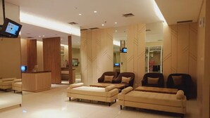Una moderna hall d'albergo con una reception, diversi divani e un grande specchio.