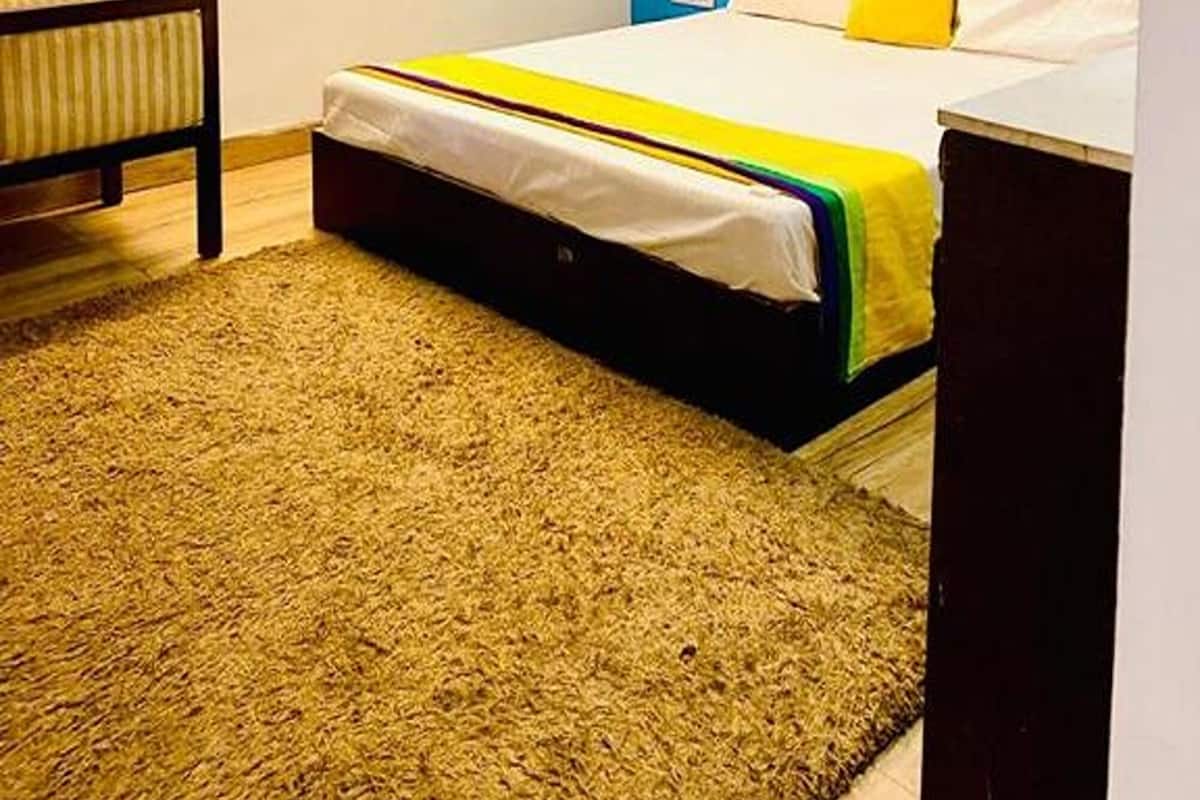 Ein Schlafzimmer mit Bett, Nachttisch, rotem Vorhang, Deckenventilator und Holzboden.