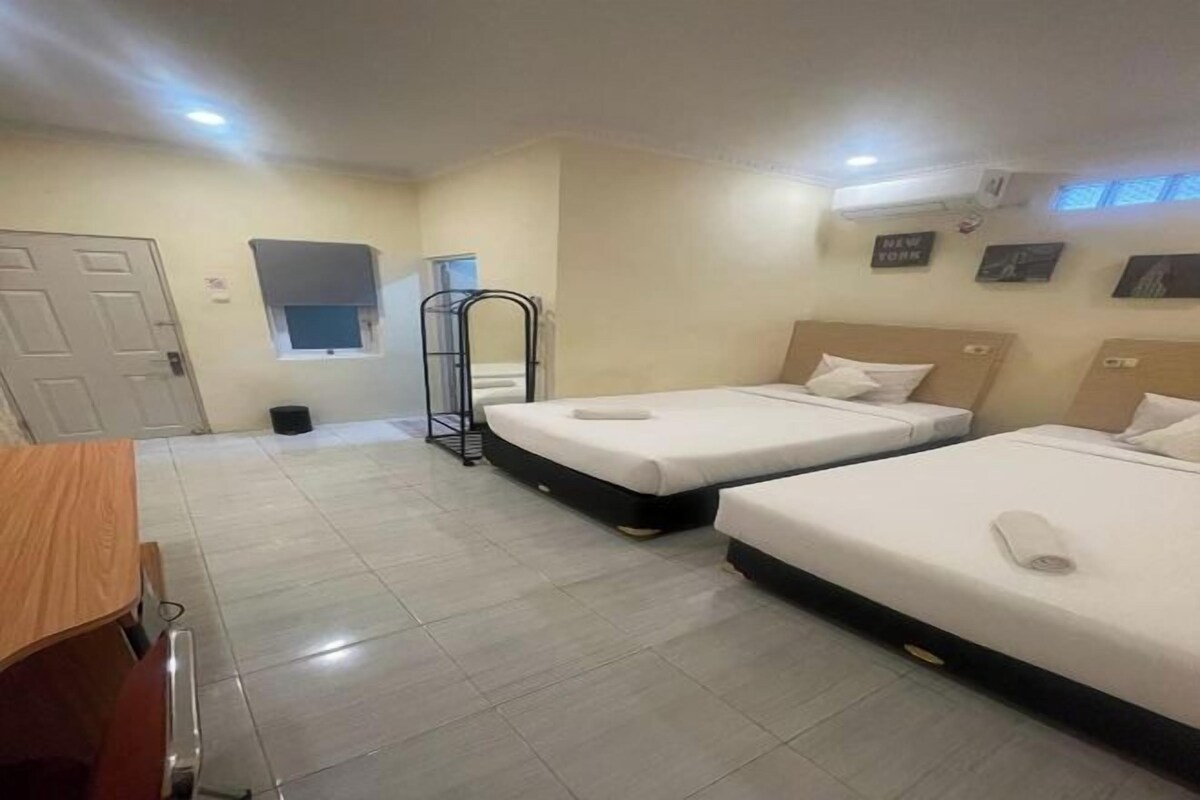 Ein Hotelzimmer mit zwei Betten, einem Schreibtisch, einem Stuhl, einem Fenster und einem kleinen Fenster über der Tür.