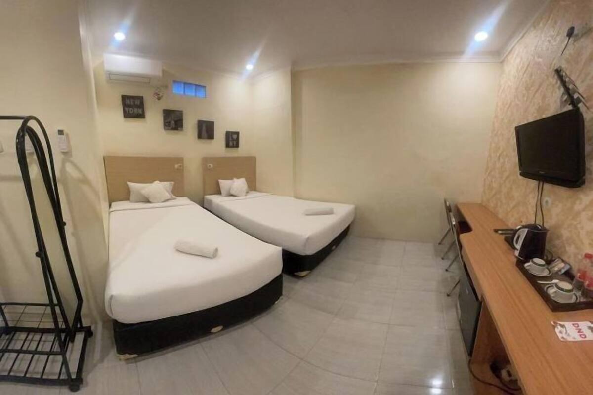 Een hotelkamer met twee bedden, een bureau, een televisie en een tv aan de muur.