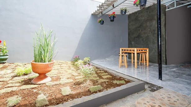 Een binnenplaats met een bloempot, een kleine tuin en een houten bank.