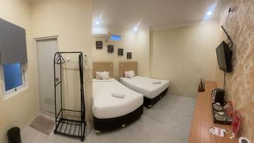 A hotel room with two beds, a desk with a coffee machine, a TV, and a shower area.