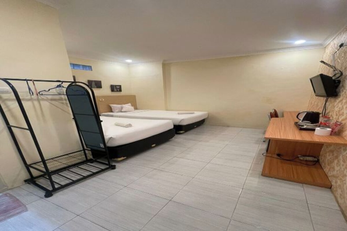 Een hotelkamer met twee bedden, een bureau, een televisie en een kapstok.