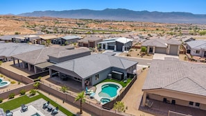 A residential area with modern houses, a swimming pool, and a view of distant mountains.