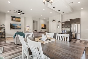 A modern kitchen with stainless steel appliances and a dining area with a wooden table and white chairs.