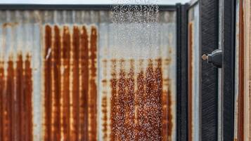 A hot tub with water jets spraying upwards, set against a backdrop of rusted metal panels.