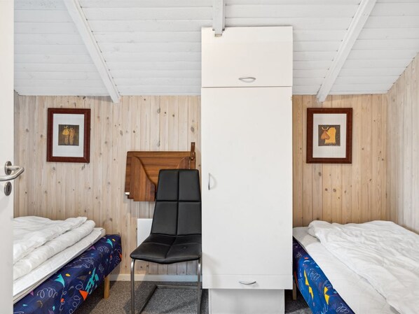 A compact room with two single beds, a desk, and a chair.