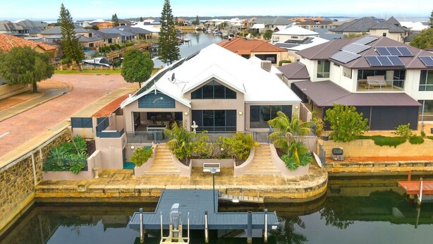 A modern house with a large front porch, solar panels, and a dock.