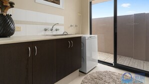 A modern kitchen with dark cabinets, a white countertop, a built-in dishwasher, and a large window offering a view of the desert.