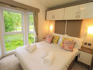 A bedroom with a large bed, two bedside tables, a wardrobe, and a window with curtains.