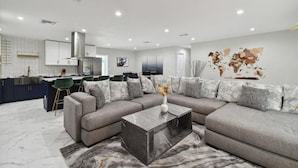 A modern living room with a grey sectional sofa, a marble coffee table, and a world map on the wall.