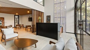 Uma sala de estar espaçosa com design moderno, equipada com uma TV de tela grande, assentos confortáveis e janelas amplas que proporcionam iluminação natural e vistas.