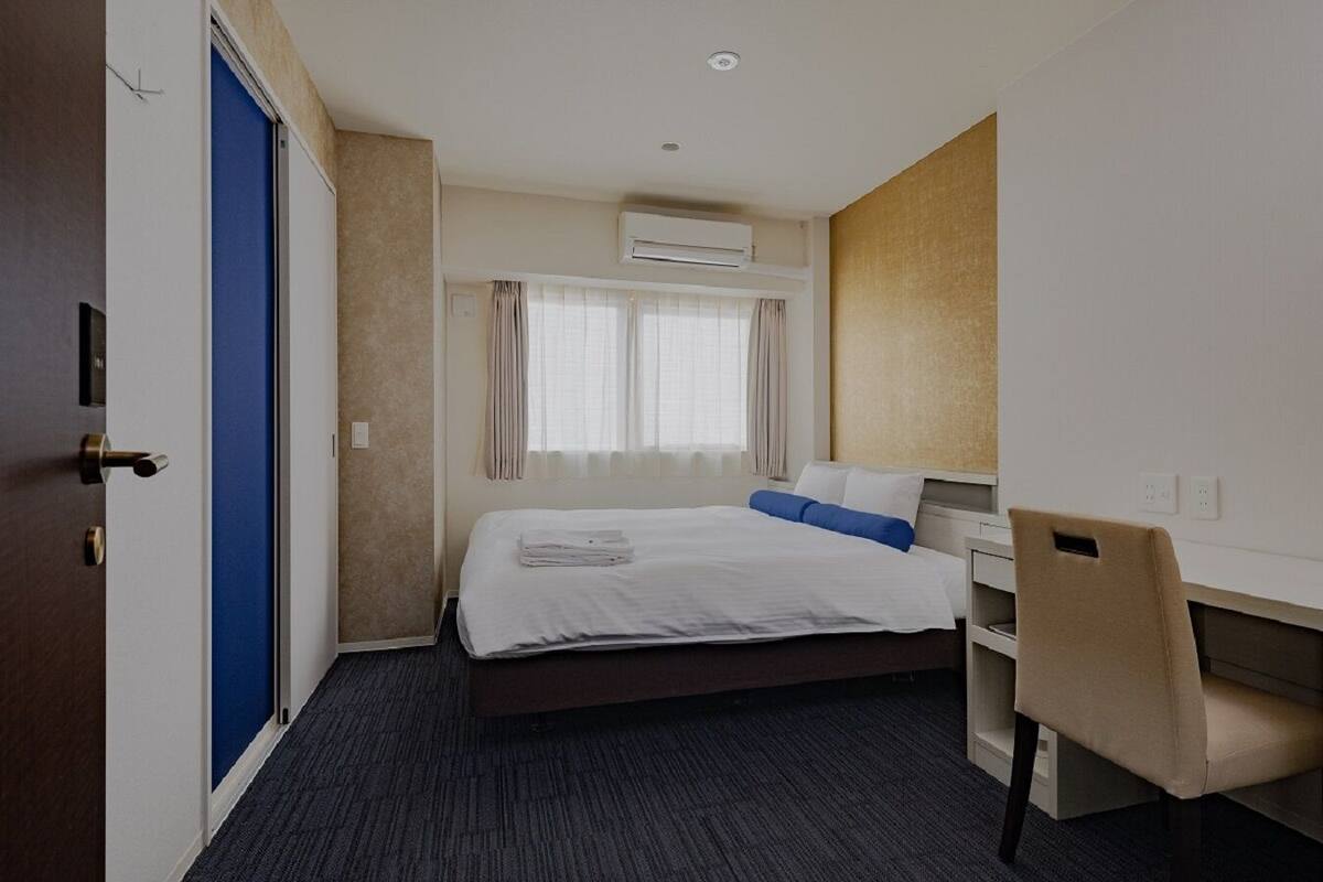 Ein Hotelzimmer mit Bett, Schreibtisch, Klimaanlage und einer Tür.