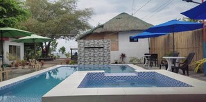 Relax by the serene pool surrounded by lush greenery and comfortable seating.