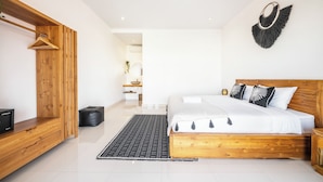 A modern bedroom with a wooden bed frame, a hanging coat rack, and a decorative wall piece. - Villa Melita - Canggu (Canggu)