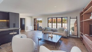 A spacious living area with a sofa set, a coffee table, and a bar area with a TV. - Monaco Resort Apartment with Access to Swimming Pool and Gym Facilities (Nelson)
