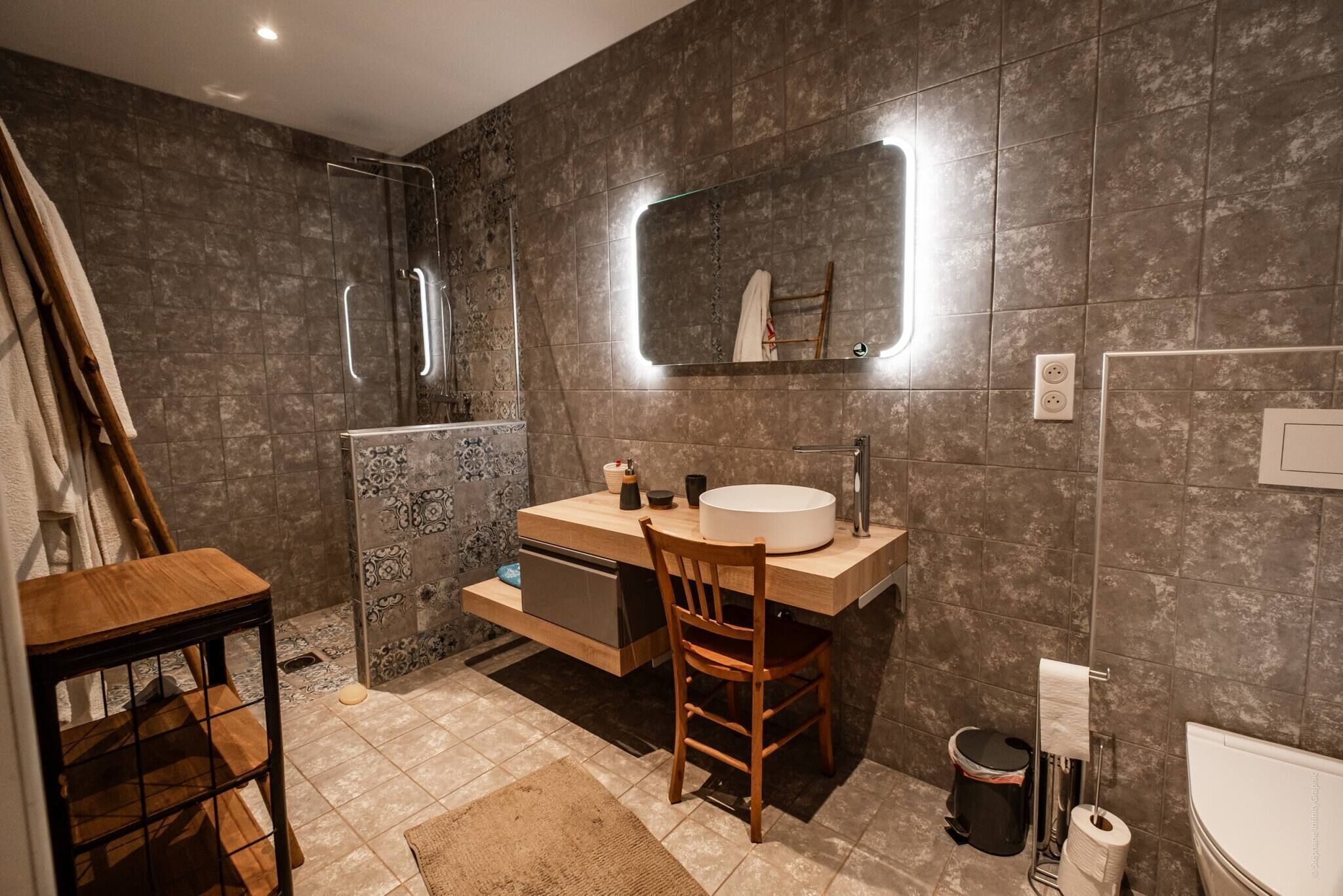 A modern bathroom with a wooden vanity, a glass shower enclosure, and a large mirror.