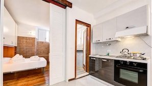 A compact kitchen with a stove, oven, and white cabinets. - Vicolo 42-private Terrace-200m Lake (Salò)