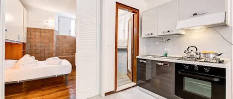 A compact kitchen with a stove, oven, and white cabinets.