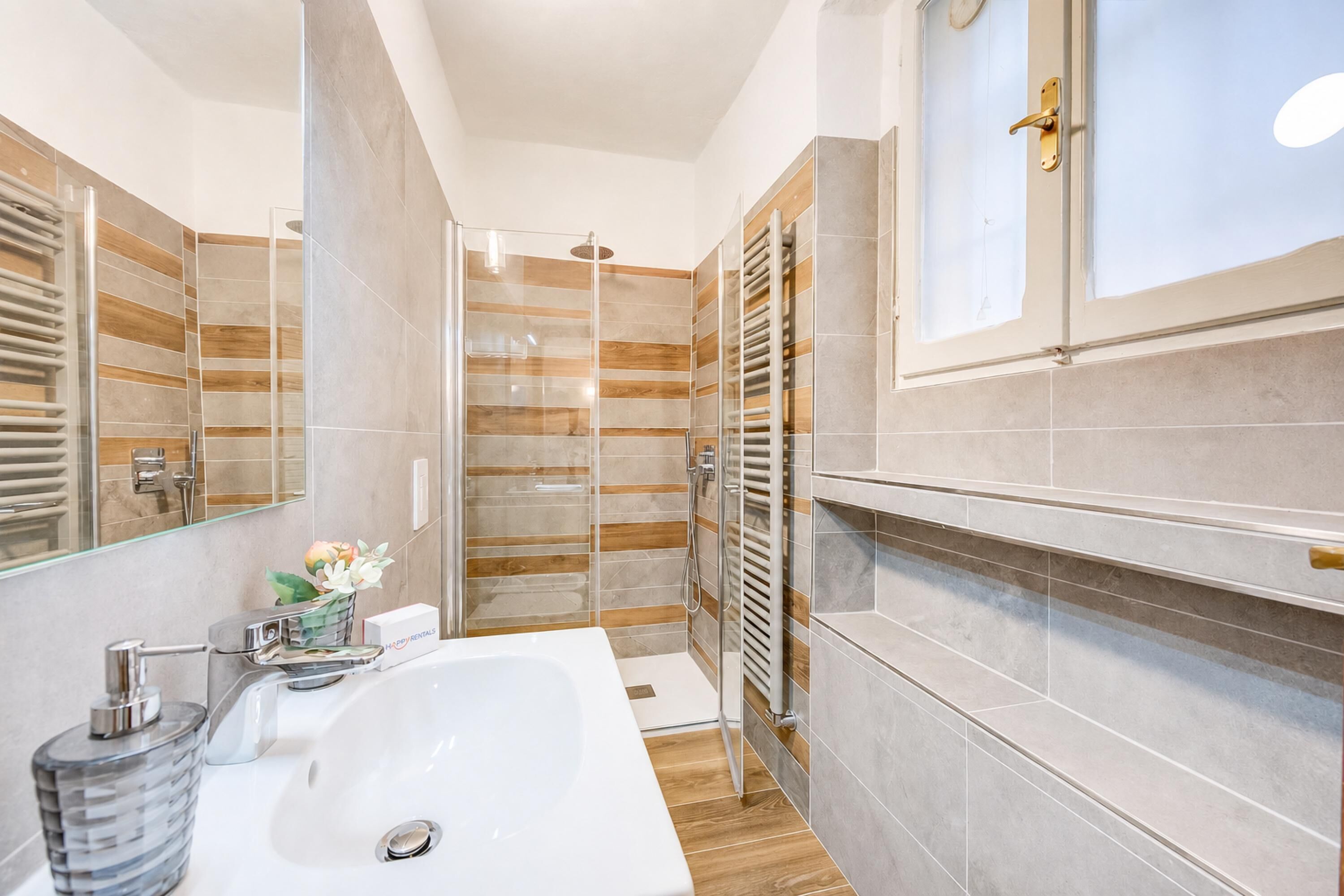 Une salle de bain moderne avec une douche à parois de verre, un grand lavabo et un porte-serviettes.