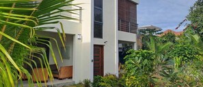 Stroll through lush gardens to a welcoming entrance with a cozy porch and a beautifully appointed door.