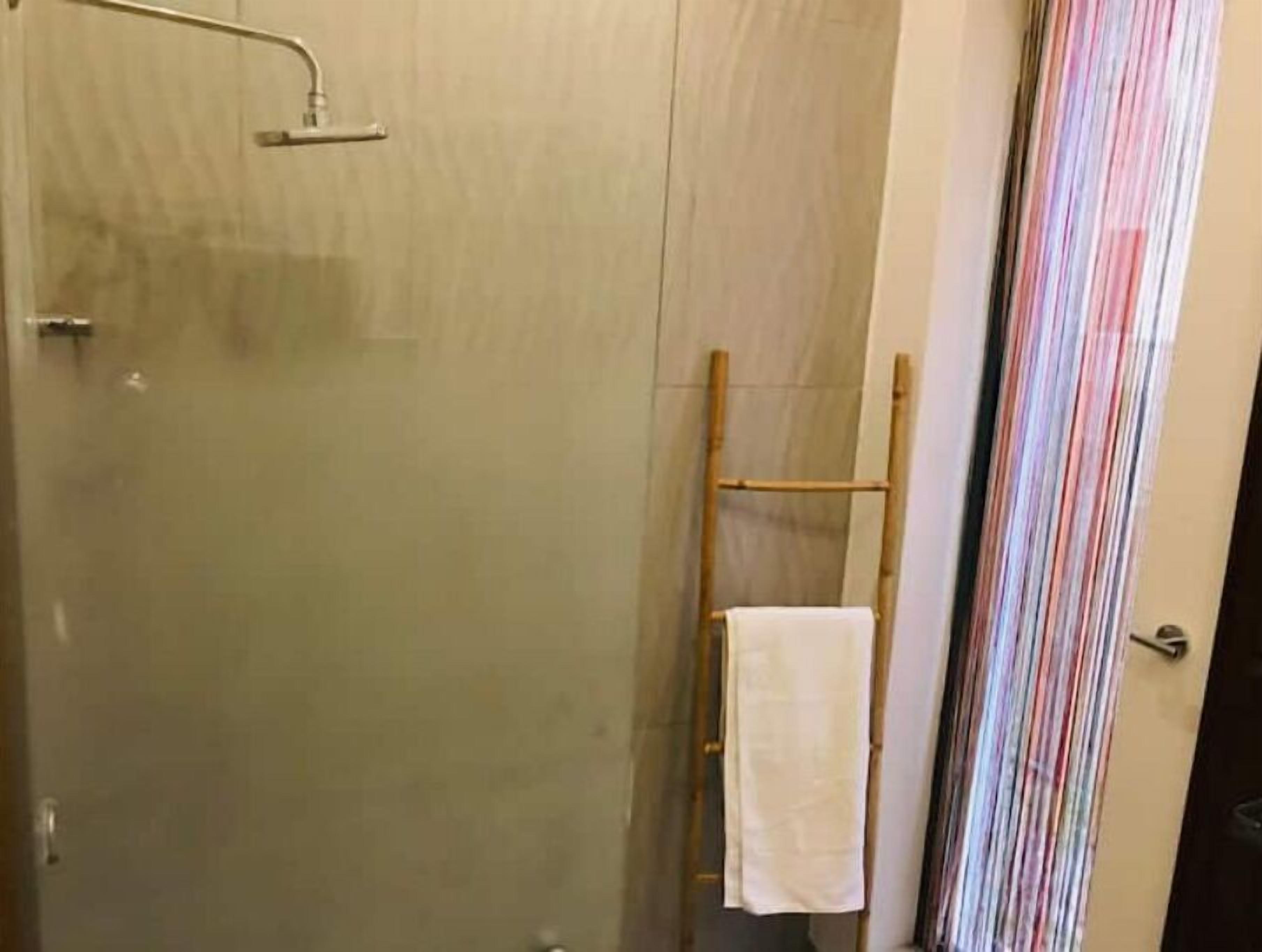A glass-enclosed shower area with a wooden ladder and a white towel hanging on it.