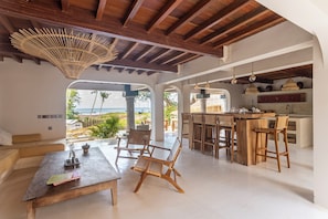 Relax in a spacious interior with a high ceiling, comfortable seating area, and large windows offering a view of the outdoors.
