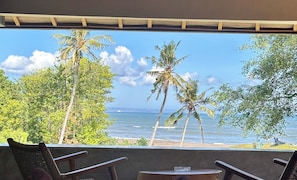 Relax in a tranquil oceanfront seating area with a wooden pergola, two chairs, and a small table.