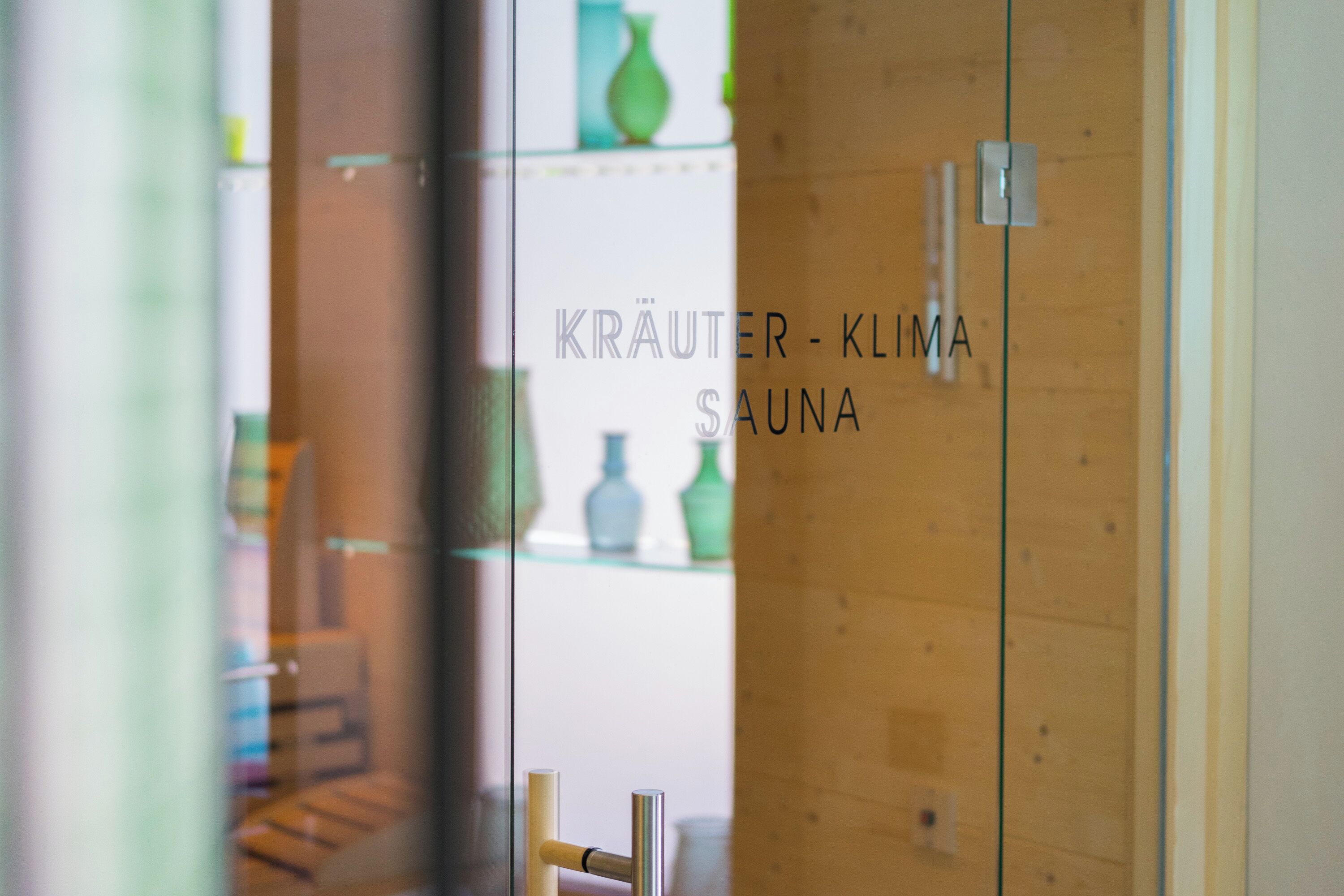 En trædør med teksten "KRAUTER - KLIIMA SAUNA", der angiver et sauna-rum.