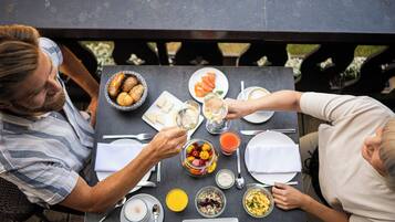 Una mesa de comedor con diferentes alimentos y bebidas, rodeada de sillas.