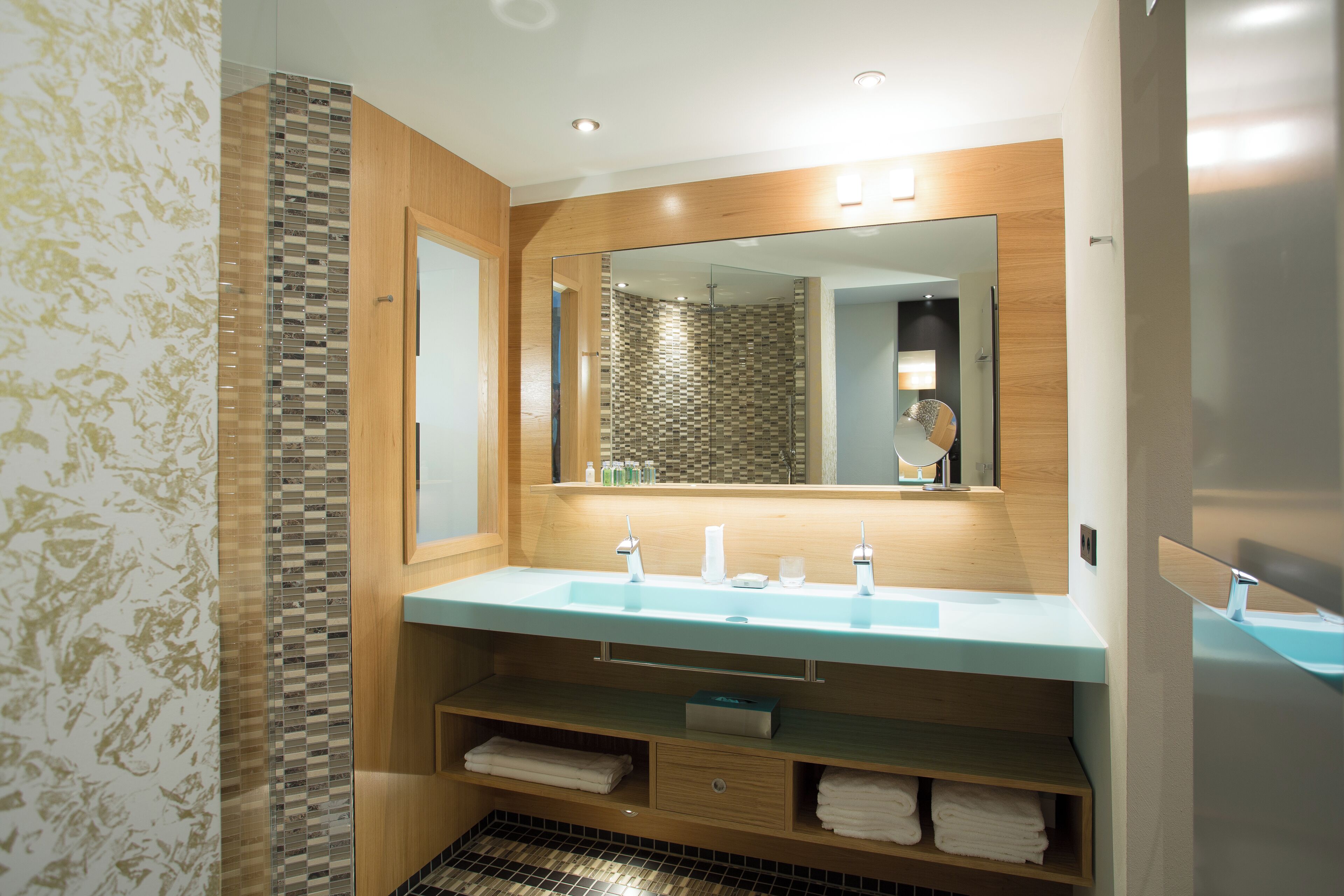 Un baño moderno con un espejo grande, un lavamanos y una zona de ducha.