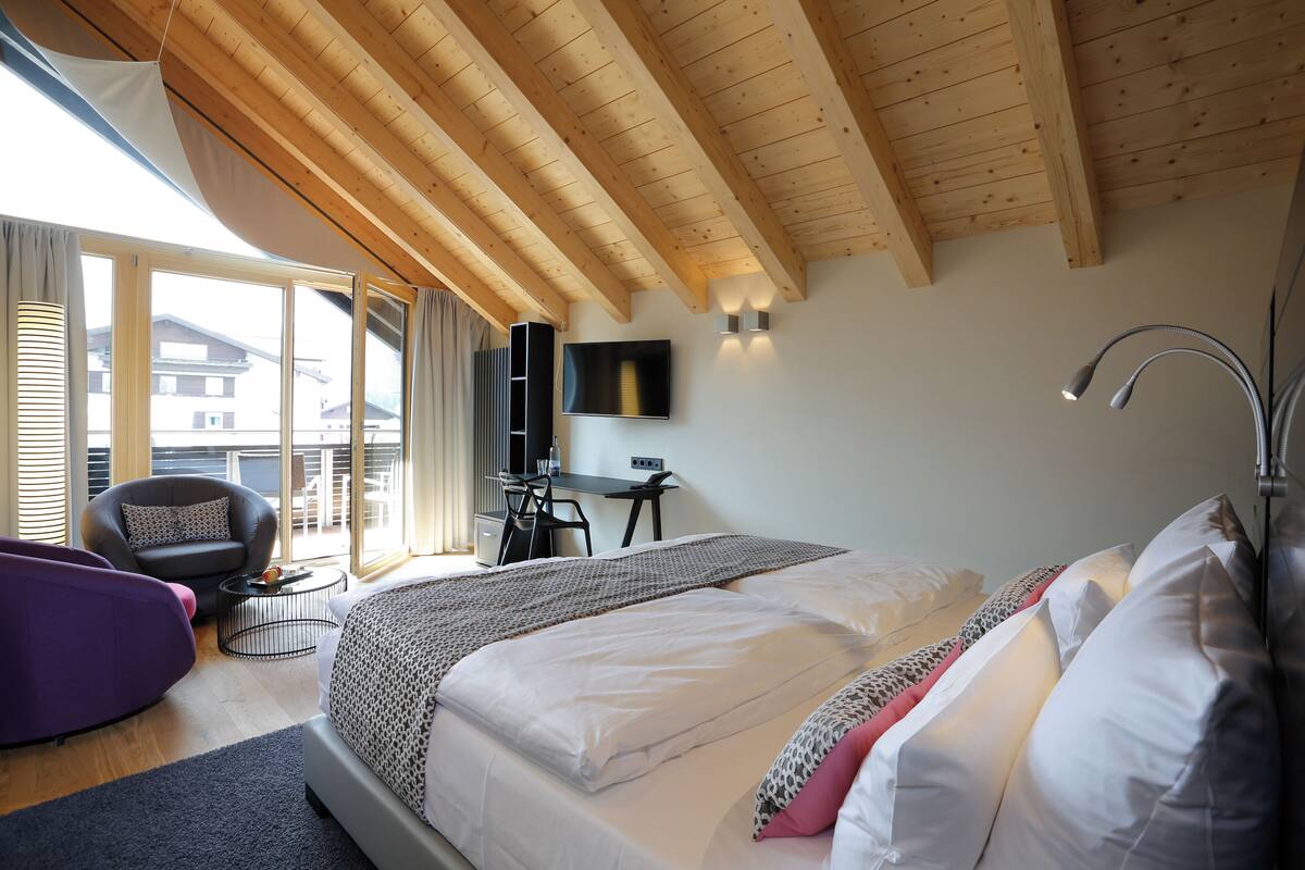 Un dormitorio con una cama grande, un escritorio, una silla y un sofá.