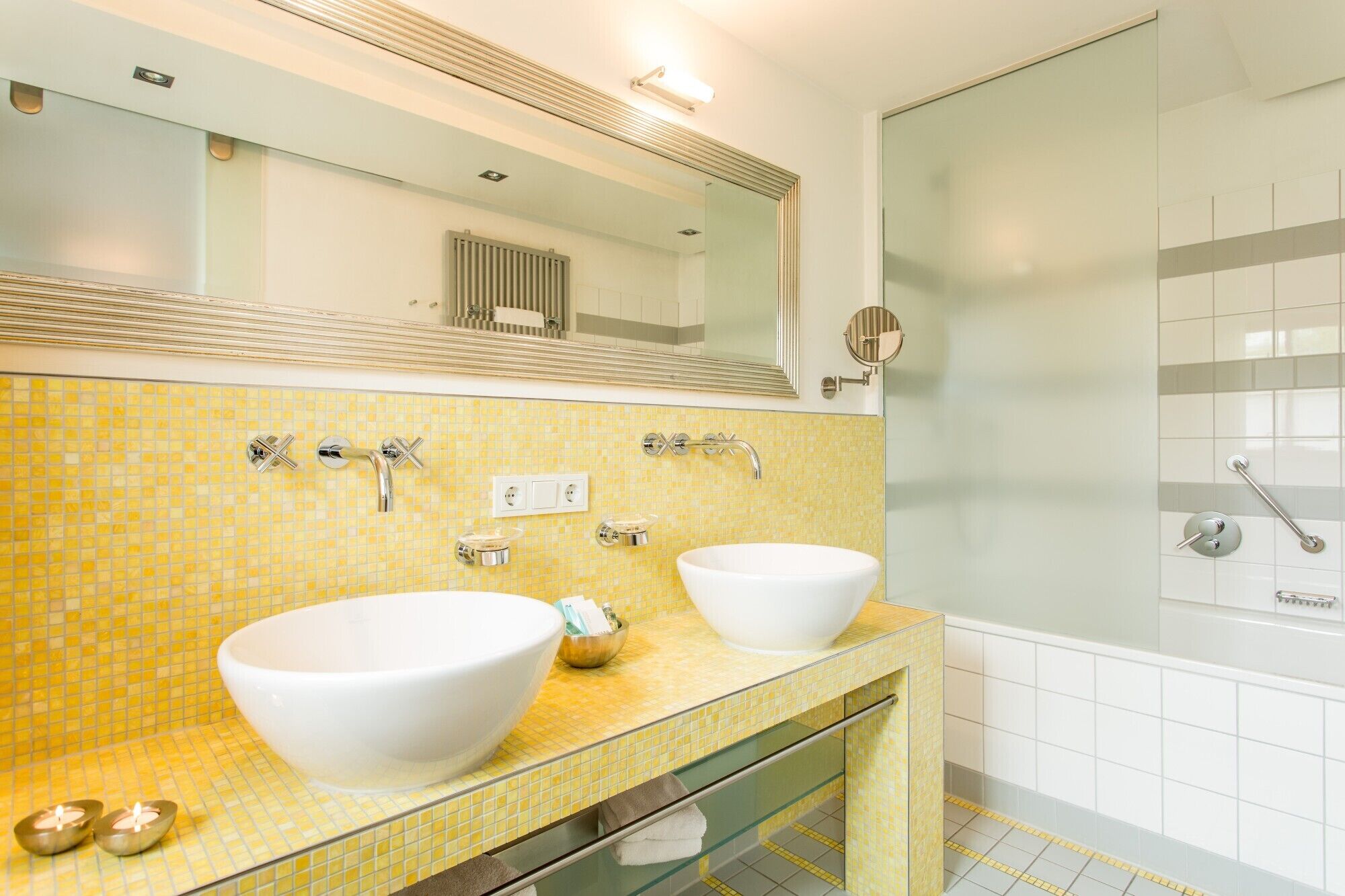 Une salle de bain avec deux lavabos, un grand miroir et une douche à parois de verre.