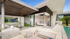 A modern outdoor living area with a pool, seating, and a glass-enclosed bedroom. - Villa Raku (Koh Samui)
