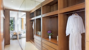 A modern walk-in closet with wooden shelving, a robe hanging, and a pair of slippers on the floor. - Villa Raku (Koh Samui)