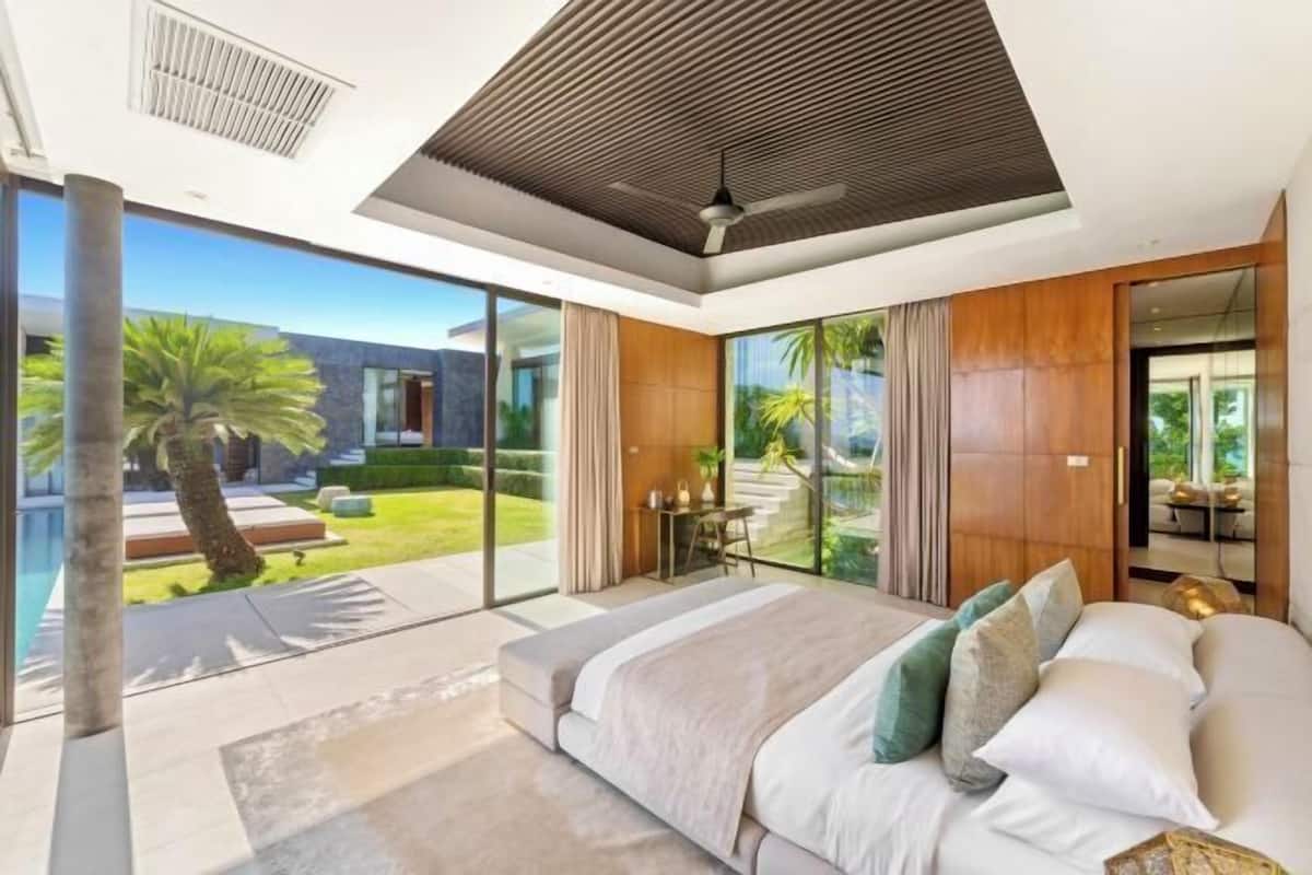 Une chambre moderne avec un grand lit, une vue sur une piscine et une porte-fenêtre coulissante donnant sur un espace extérieur.