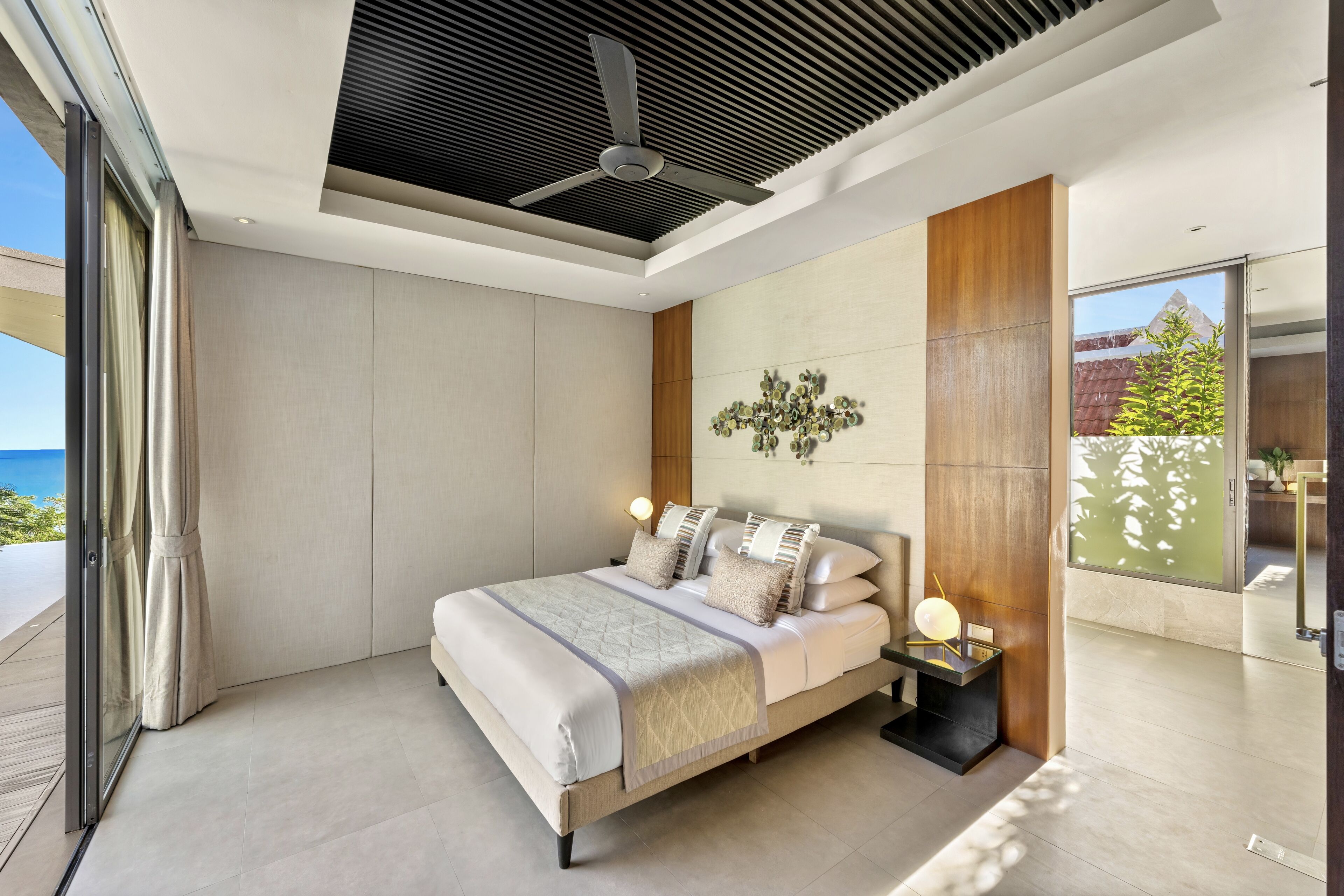 A modern bedroom with a bed, bedside table, and a view of the outdoors.
