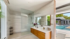 A modern bathroom with a glass-enclosed shower, a marble vanity, and a large mirror. - Villa Raku (Koh Samui)