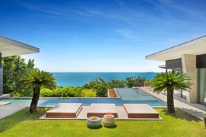 A modern outdoor pool area with lounge chairs and a view of the sea. - Villa Raku (Koh Samui)
