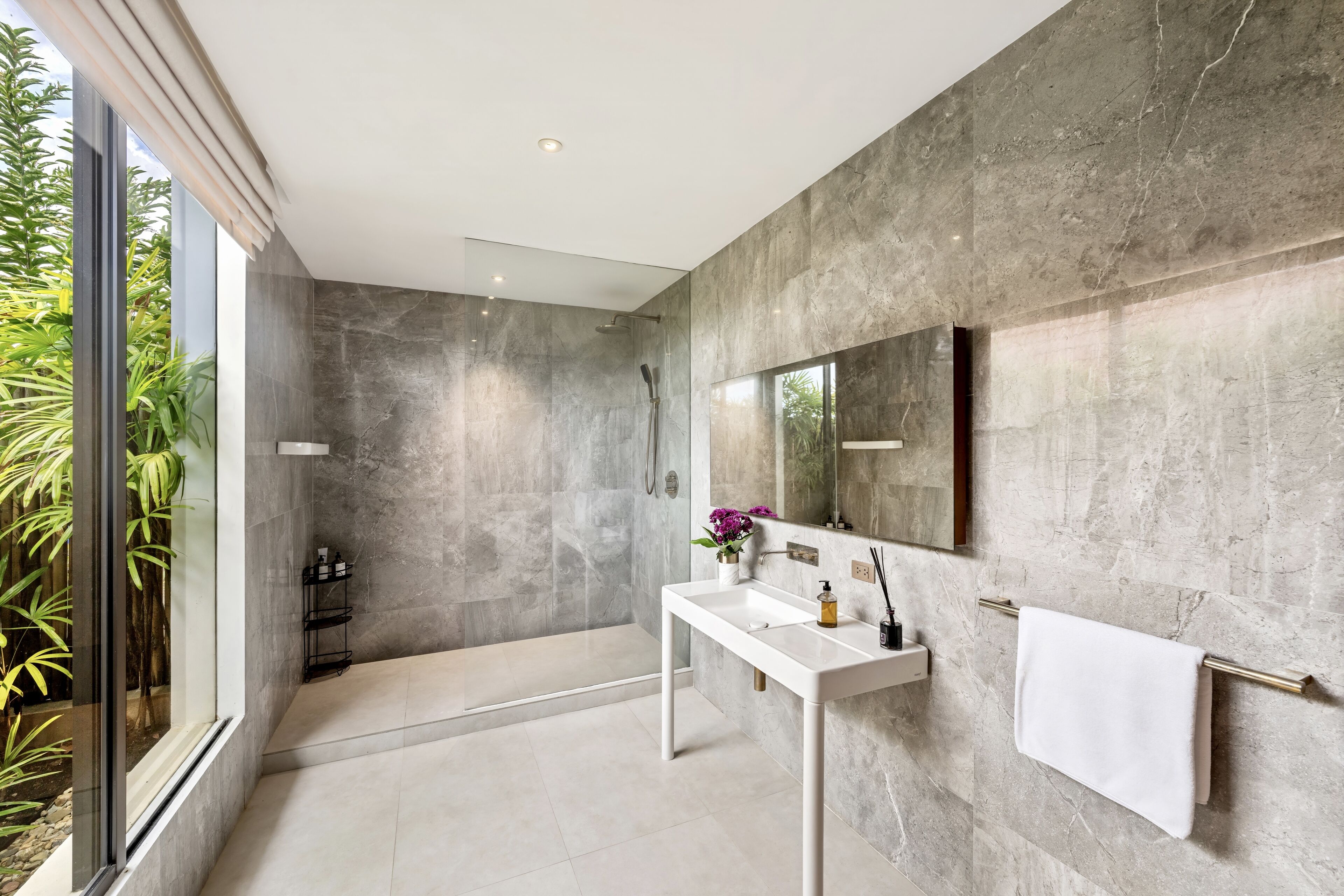 Un baño moderno con un espejo grande, un lavamanos blanco y un perchero para toallas.