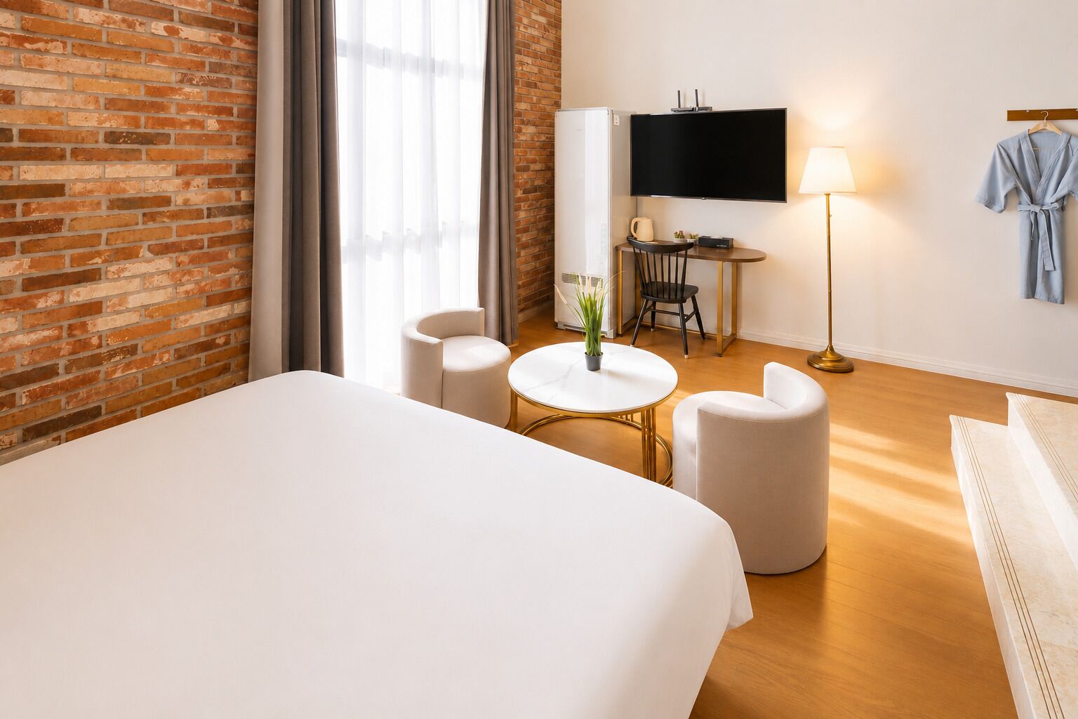 Habitación de hotel con una cama grande, una mesa redonda con dos sillas, un televisor y una lámpara.
