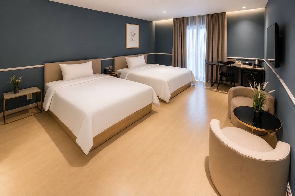 Quarto de hotel com duas camas, uma escrivaninha, uma cadeira e uma televisão.