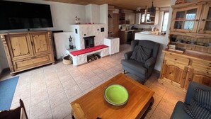 A cozy living room with a fireplace, a television, and wooden furniture. - Charming log chalet at 1200 m – CAR-FREE, access by gondola only (Emmetten)