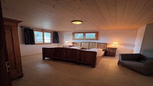 A bedroom with a wooden bed, two bedside tables with lamps, a window with curtains, and a wooden wardrobe. - Charming log chalet at 1200 m – CAR-FREE, access by gondola only (Emmetten)